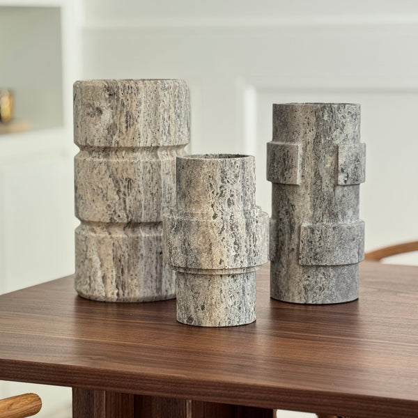 Set of stone-textured cylindrical vases on a wooden surface with a blurred background
